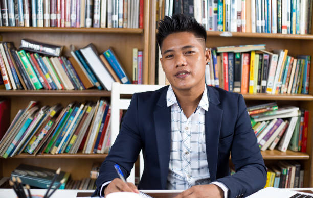 istock Southeast Asian guy from Malaysia studying in a library wearing a shirt with a suit 1442912370