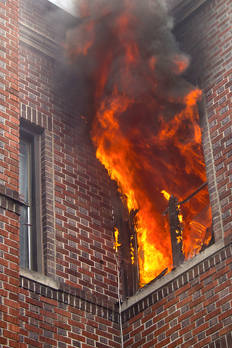 A vertical shot of a burning apartment in a building in the daylight