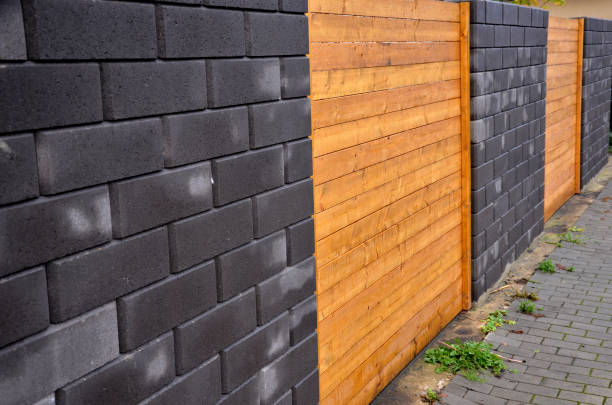 istock garden fencing where materials such as wood and rectangular concrete blocks are combined. between the walls are embedded pieces with planks. wet after rain 1442913352