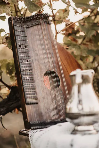 A vertical closeup of a brown zither on the table outdoors.