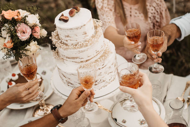 Closeup of the wedding table with cake and people holding glasses with beverages. A closeup of the wedding table with cake and people holding glasses with beverages. wedding cake stock pictures, royalty-free photos & images
