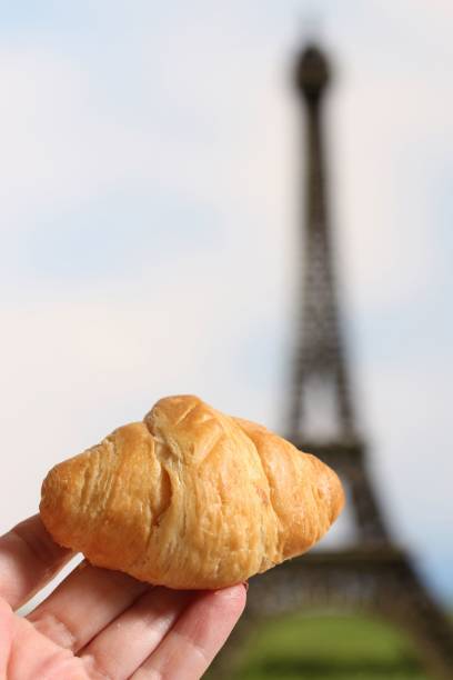 istock Fresh Croissant Roll in Hand With Eiffel Tower in Background 1442914890