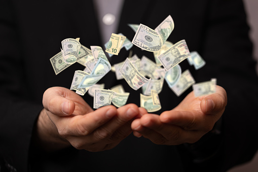 A 3D rendering of US banknotes on a businessman's palms