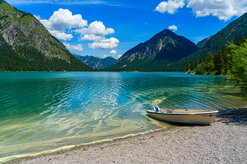 A wooden boat moored on a tranquil lake with mountain ranges background