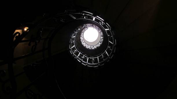 istock Bottom view of a spiral staircase with a bright light at the end 1442915639