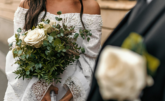 Selective focus image of bride holding beautiful white and green wedding bouquet