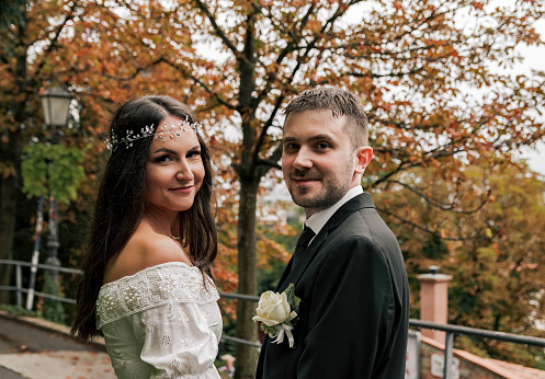 Young bride and groom posing for a photo in park on a moody autumn day.