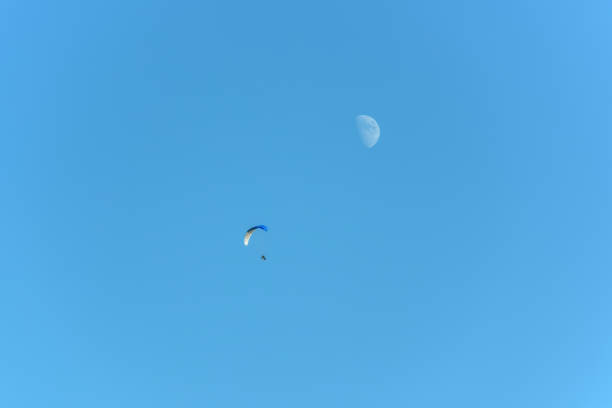 istock Paramotor in flight on a sunny day with the moon in the sky. 1442922937
