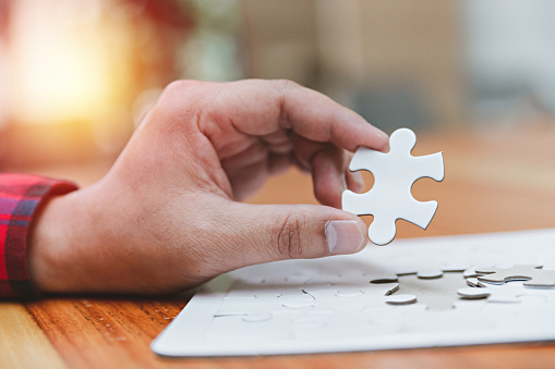 Business man use white puzzle piece brainstorming and solution concept, engineer man connect jigsaw puzzle, concept success and strategy, asian young hold jigsaw puzzle.