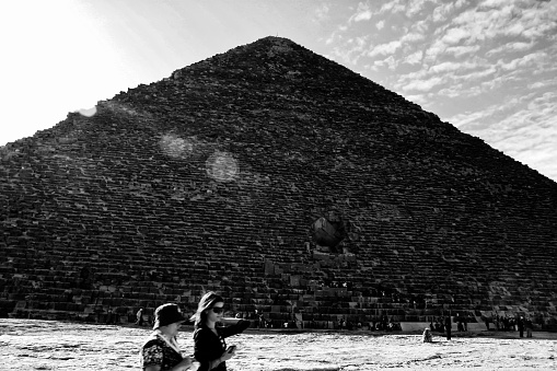 Giza, Egipt. Dec 09, 2008 Great Pyramid of Giza. also known as the Pyramid of Khufu or the Pyramid of Cheops. two passing tourists. black and white photography