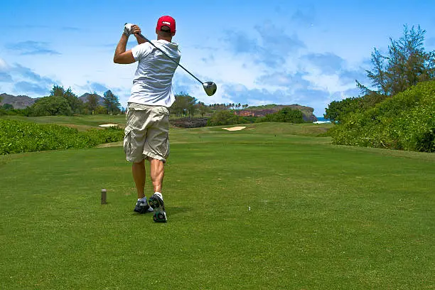 Guy driving a golf ball on a golf course in Hawaii.