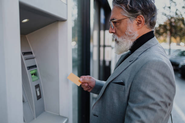 istock Senior business man using atm machine and credit or debit card 1442929437
