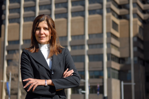 Business woman with crossed arms in front of a corporate office