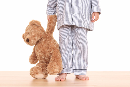 boy in pijama with his teddy bear isolated on white