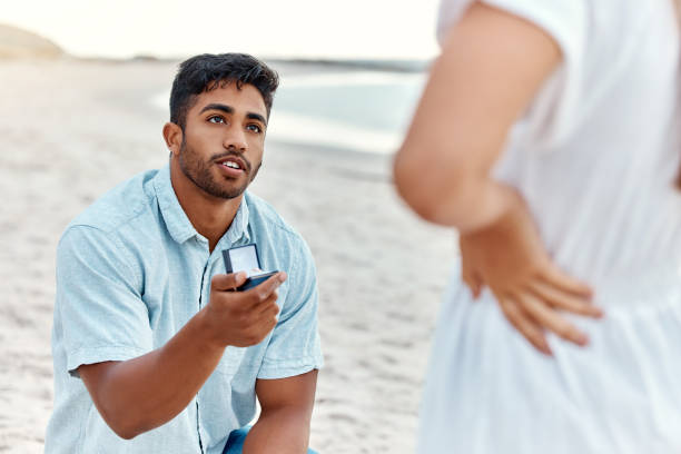 istock Engagement ring, man and beach proposal for surprise, love and relationship commitment to girlfriend. Young, engaged and marry me couple, summer seaside date and special romance marriage outdoors 1442930747