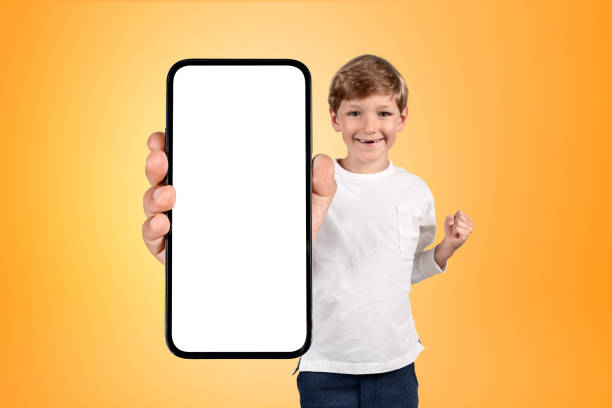 istock Happy boy with a fist, large phone mockup display on grey backgr 1442931139
