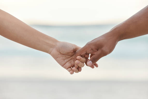 istock Touch, love and support with interracial couple holding hands in a committed, loving and close relationship. Closeup hands of man and woman enjoying beach travel, sea vacation or holiday and romance 1442932023