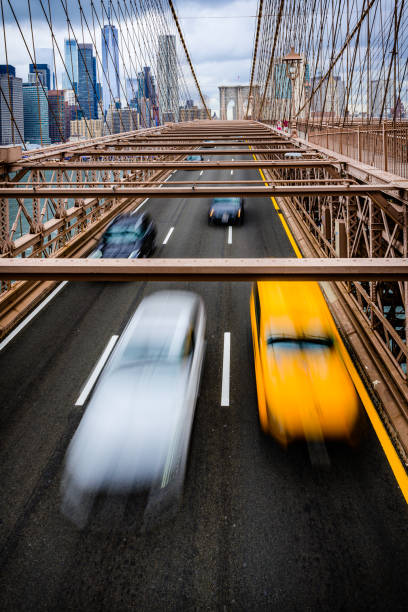 poruszająca się taksówka i inne samochody na moście brooklińskim z centrum nowego jorku w tle. - brooklyn bridge taxi new york city brooklyn zdjęcia i obrazy z banku zdjęć