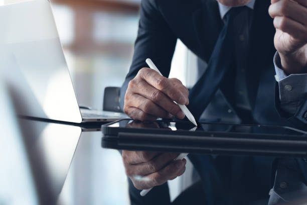 istock Businessman using stylus pen signing e-document on digital tablet with laptop computer on table at office, e-signing, electronic signature, paperless office 1442932879