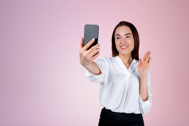 istock Businesswoman with phone in hand, waving on empty blue background 1442933721