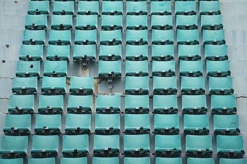 Row of empty green seating chair at cheering stand in the sport stadium. Sport equipment object photo.