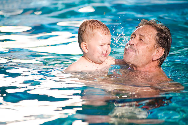 Grandfather swimming with grandson stock photo