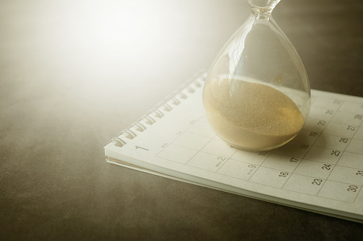 Close view of sand flowing through an hourglass. 
