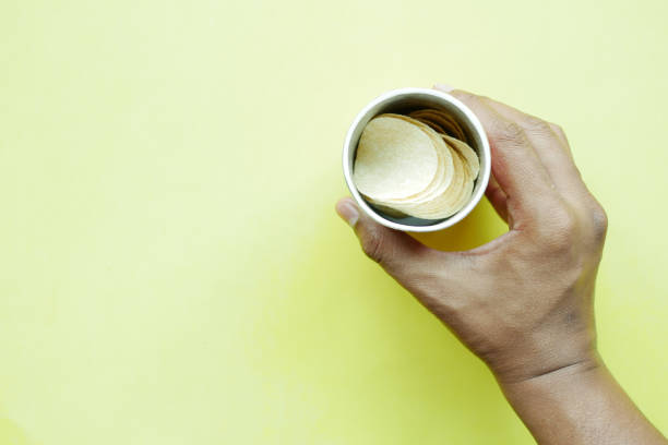 istock top view of holding a chips container on yellow background 1442944690