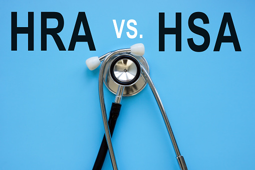 Words HRA vs HSA and a stethoscope on the blue surface.