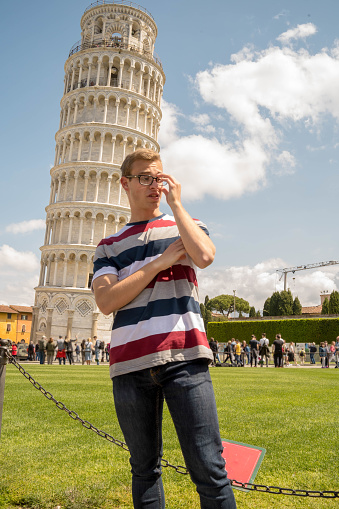 Young lucky man and leaning tower in background on Sunny day