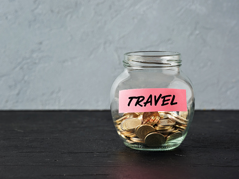 Frasco de vidrio con monedas y la palabra viajar en una etiqueta. Ahorro de dinero para viajes de vacaciones y presupuesto para vacaciones. photo