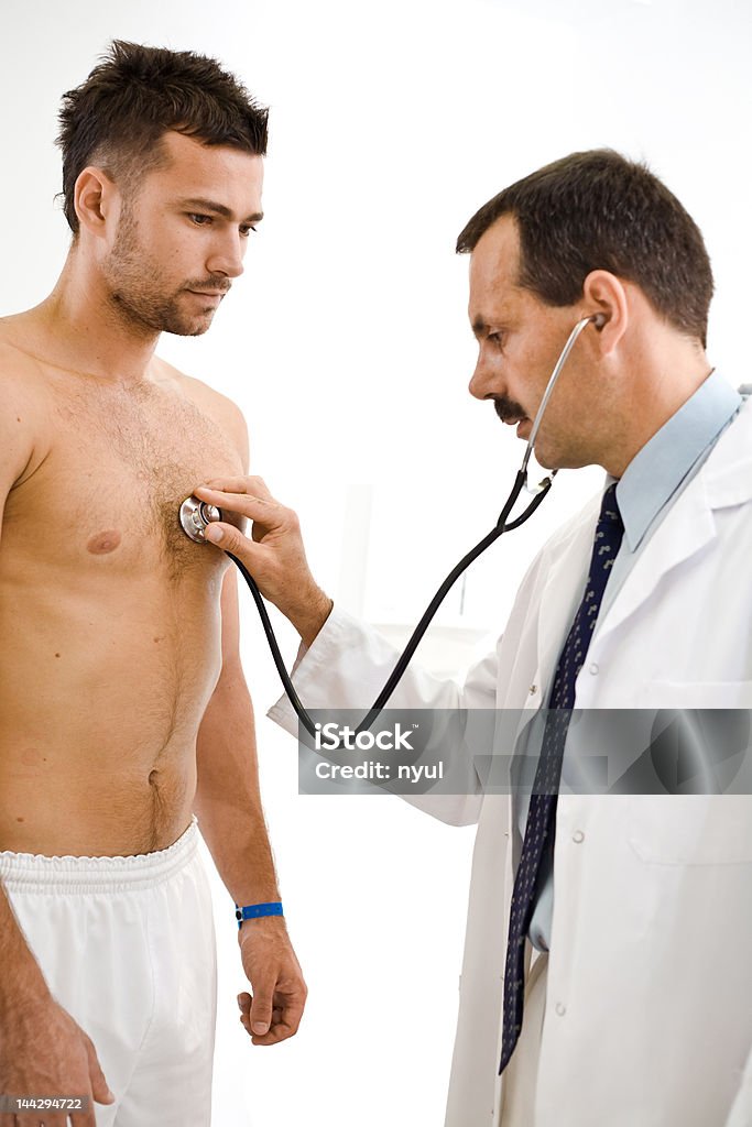 Doctor and Patient Doctor is hearing the heart beats of a young male patient. Listening Stock Photo