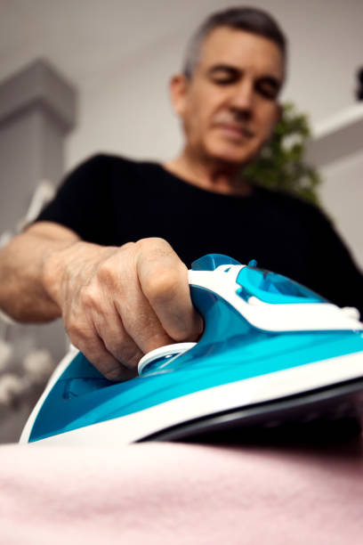 istock 60-year-old man doing housework, ironing clothes, 1442947532
