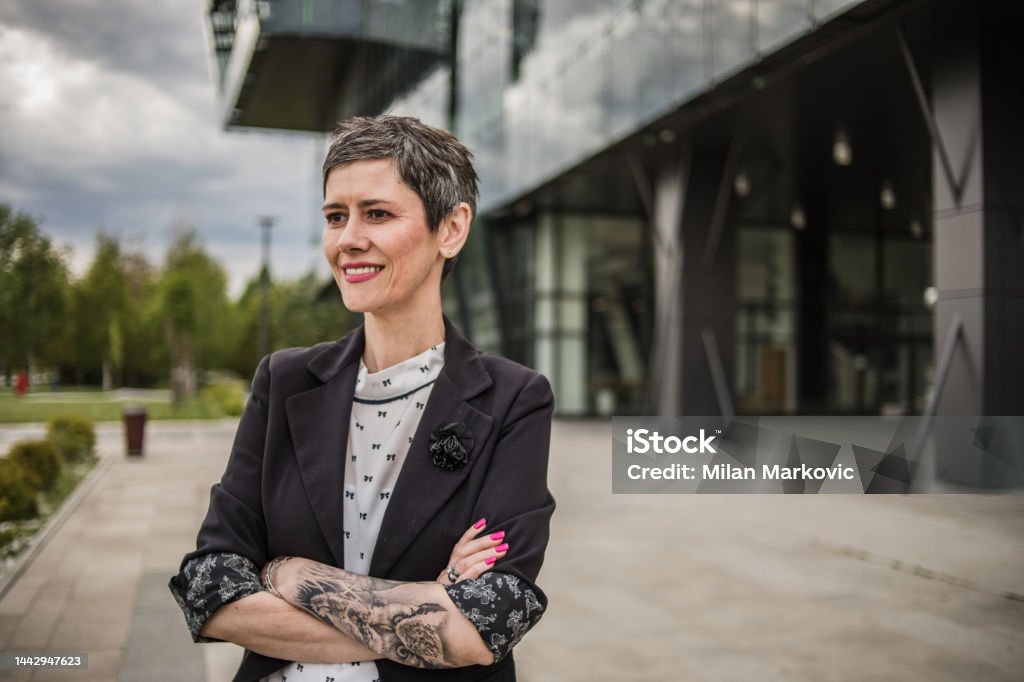 Portrait Of A Modern Business Woman With Short Hair And Tattoos On Her Arm  Standing With Crossed Arms In Front Of A Modern Office Building Stock Photo  - Download Image Now - iStock