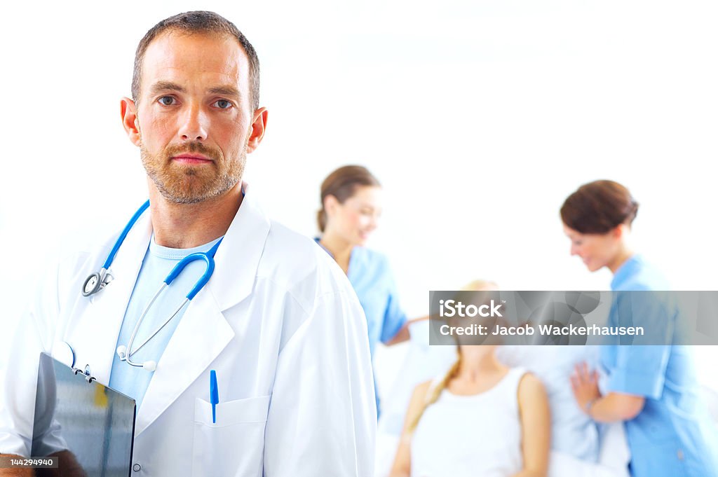 Médico com duas enfermeiras e um paciente no fundo - Foto de stock de Exame Médico - Procedimento Médico royalty-free