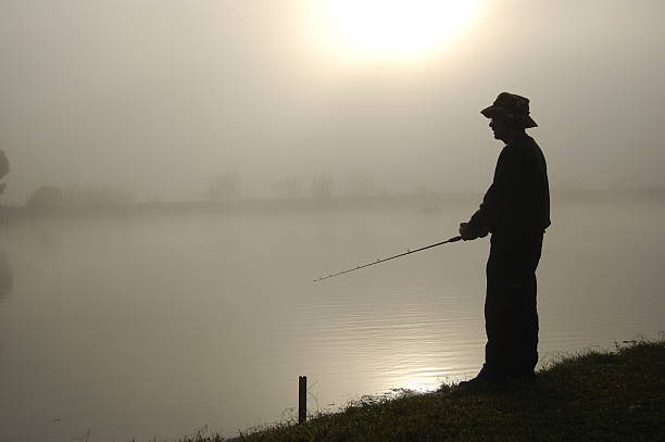 A female angler on a beach in early morning light fishing.