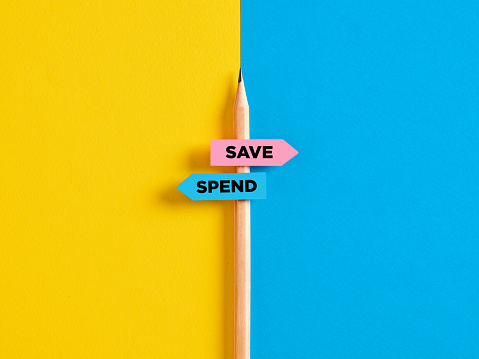 To save or to spend choice or decision. Pencil with direction indicator stickers showing the different decision paths to save or to spend money.