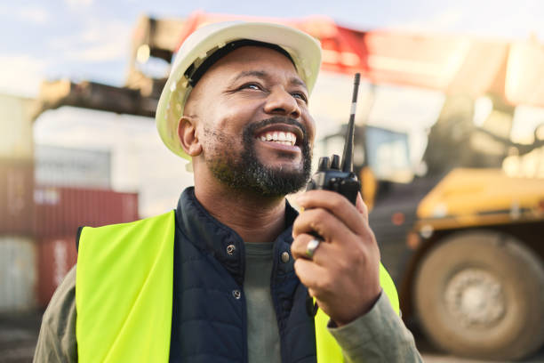 hombre que utiliza la comunicación por radio, la logística de envío y la gestión de la cadena de suministro para organizar el inventario. stock de carga de carga, contenedor comercial para exportaciones y almacenamiento de importación en un almacén d - shipyard construction industry built structure fotografías e imágenes de stock