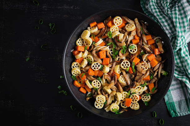 Rotelle pasta gluten free with mushrooms and pumpkin on a dark background. Vegetarian, vegan  food. Italian cuisine. Top view stock photo