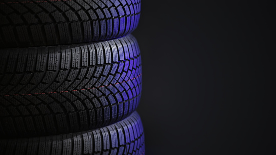 Close-up of wet vehicle tyre against black background.