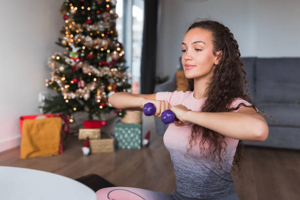 mujer en forma concentrada en el levantamiento de pesas en casa - holiday healthy lifestyle weight christmas fotografías e imágenes de stock