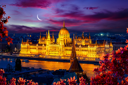 Facade of illuminated Budapest Parliament under cloudy sky, Hungary