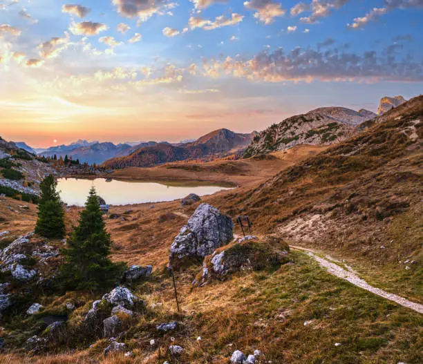 Early morning autumn alpine Dolomites mountain scene. Peaceful Valparola Pass and Lake view, Belluno, Italy.   Picturesque traveling, seasonal, and nature beauty concept scene.