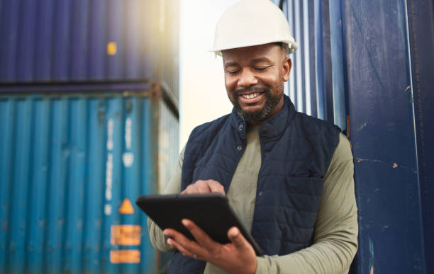 african american shipyard worker, shipping logistics and transportation of international commercial goods. tablet for inventory management, import and export of cargo in the distribution supply chain - ship freight transportation cargo container sea imagens e fotografias de stock