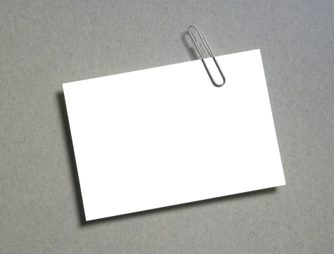blank note card and paper clip on a gray background