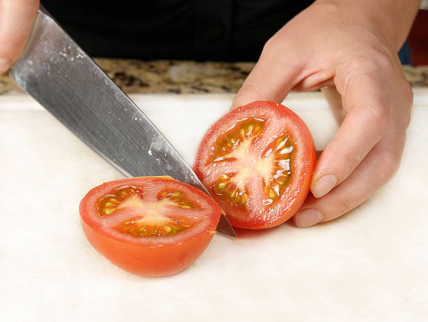 Cutting tomatoe with knife stock photo