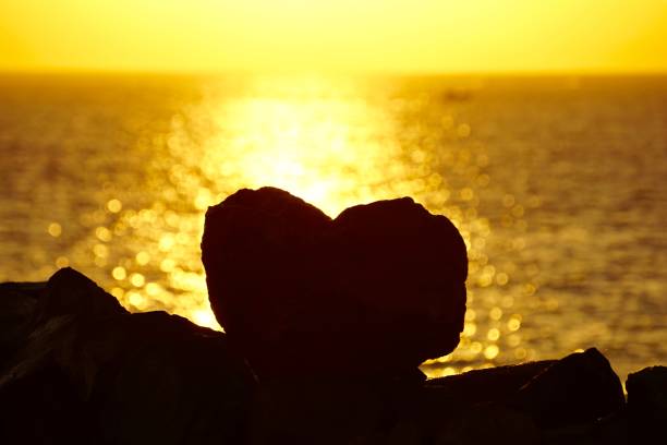 Sunset in Vladivostok and the silhouette of a heart-shaped stone opposite the sea, mountains and sunset. una piedra en forma de corazón al atardecer. la silueta de una piedra en forma de corazón frente a la puesta de sol. la silueta de un corazón en una brillante puesta de sol. una piedra en forma de corazón frente al mar y la puesta de sol.