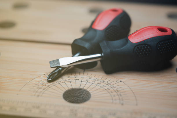 Flat screwdriver and Phillips screwdriver On woodworking workbench surface, small manual screwdriver, close-up