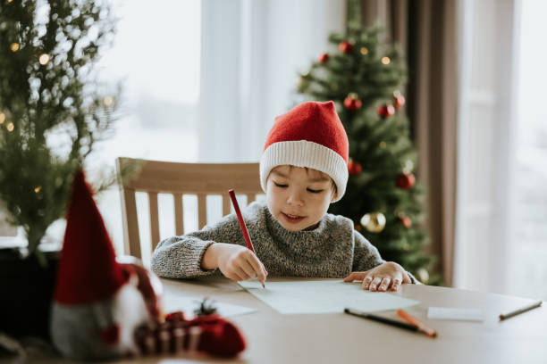 Boy writes a letter to Santa Clause Photo series of Japanese mother with her son preparing for Christmas holidays - sending Christmas letter to Santa Clause. correspondence stock pictures, royalty-free photos & images