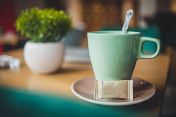 A large cup of coffee on the table, a spoon and a towel and a curtain in the background - cute cozy home